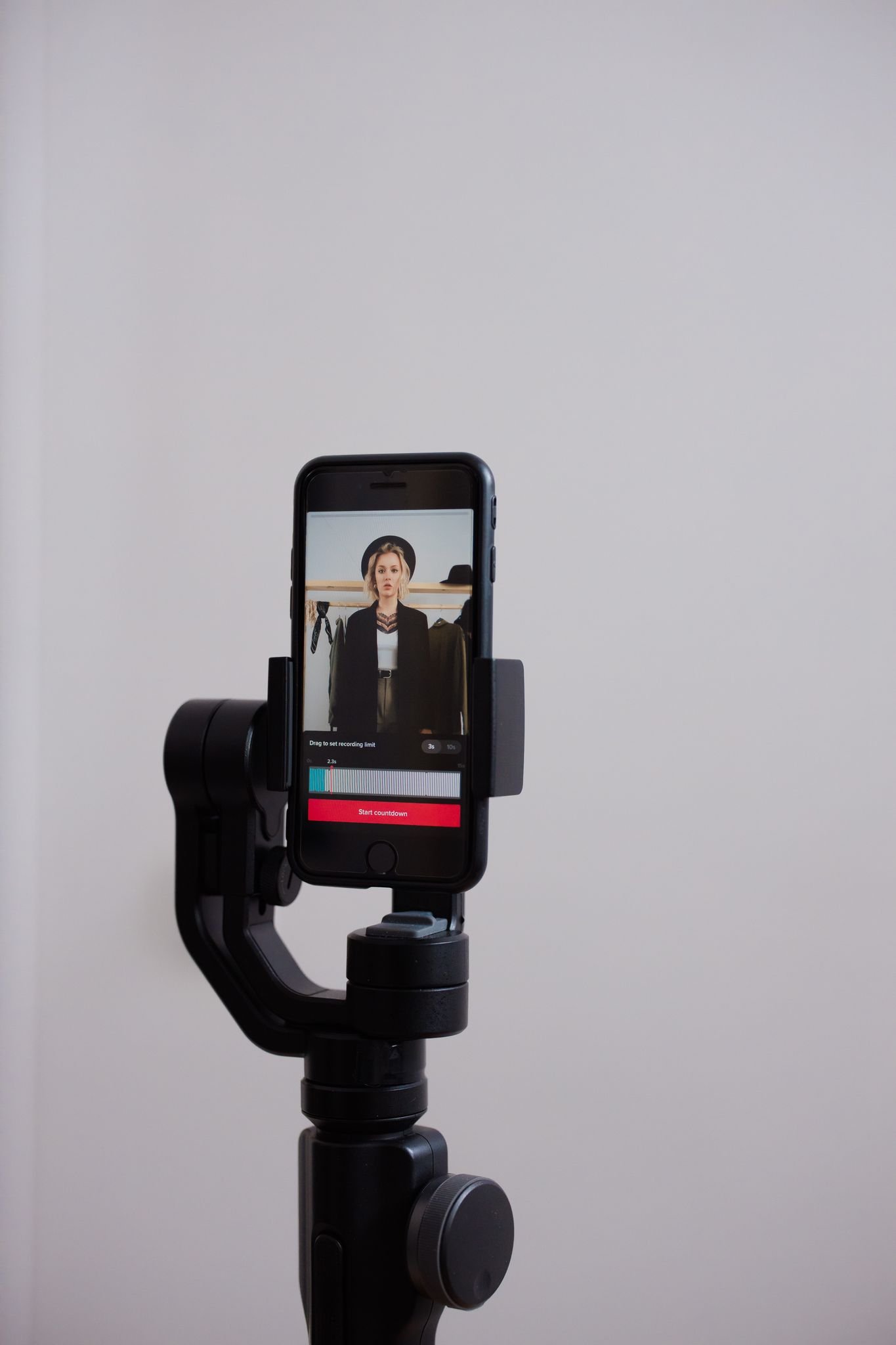 Smartphone on a tripod with a person in the screen, live streaming indoors.