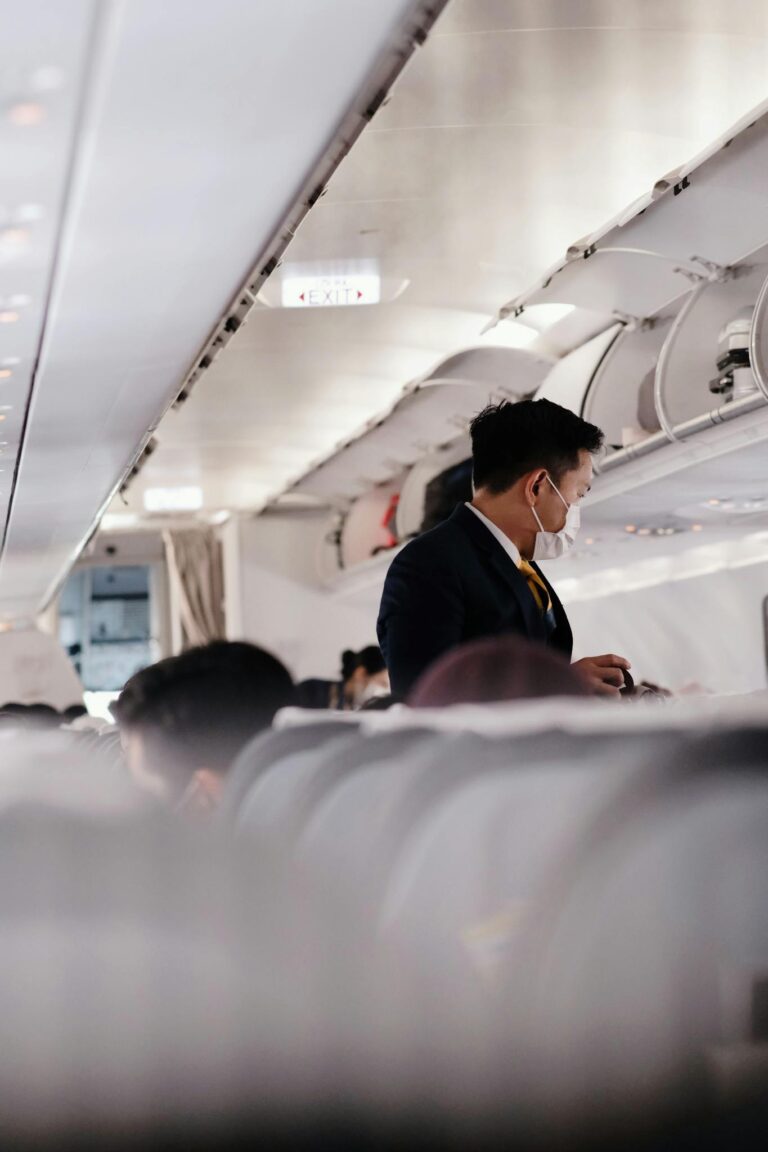A flight attendant wearing a mask assists passengers on a commercial flight.