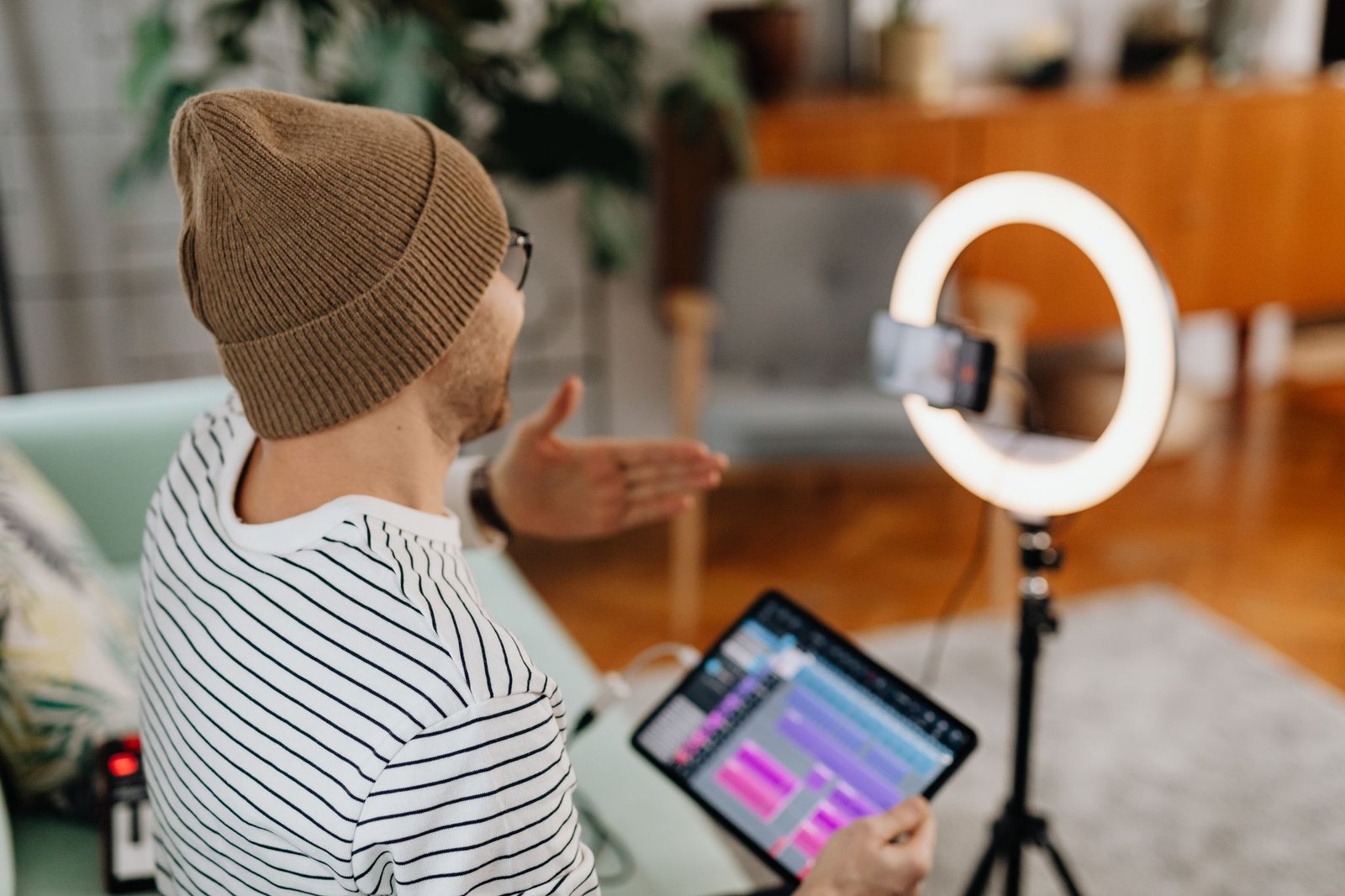 Adult male recording podcast using tablet and cellphone with ring light indoors